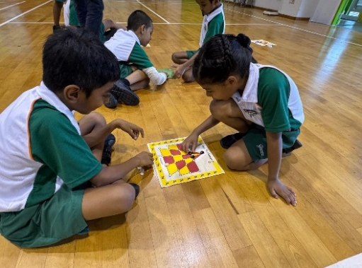 Students playing a Tamil language board game during a learning activity.